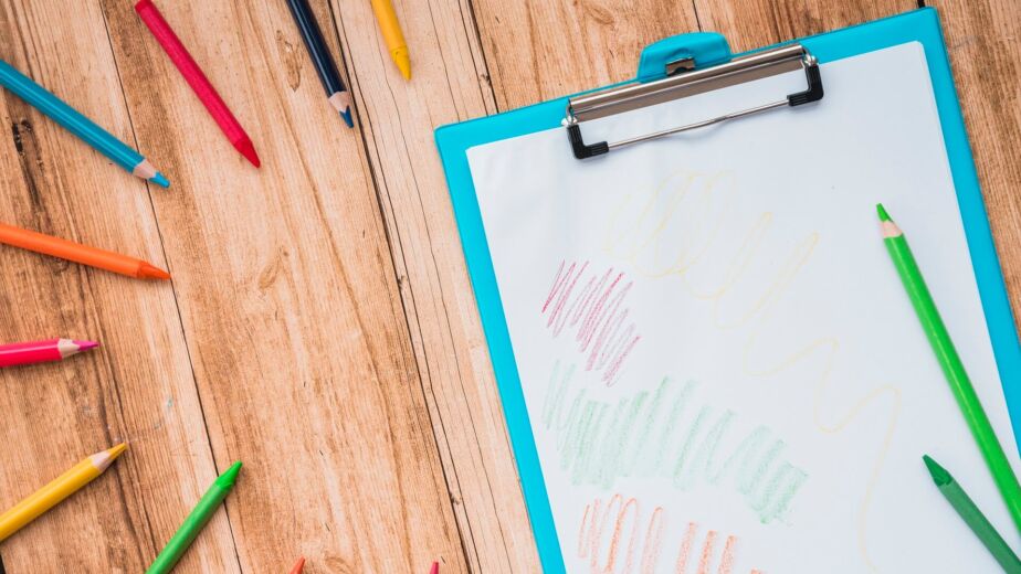 colorful pencil clipboard with white paper wooden table (1)